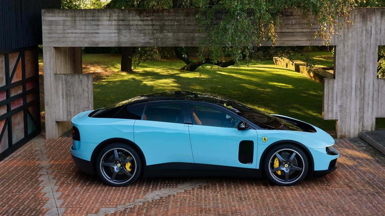 Ferrari Luce azul clara de perfil diante de uma estrutura de concreto